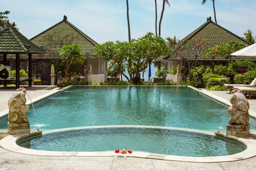 Swimming pool framed by two Balinese pavilions and stone guardian statues