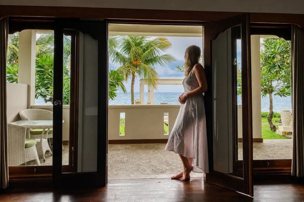 Guest standing in an open villa doorway looking out to the sea