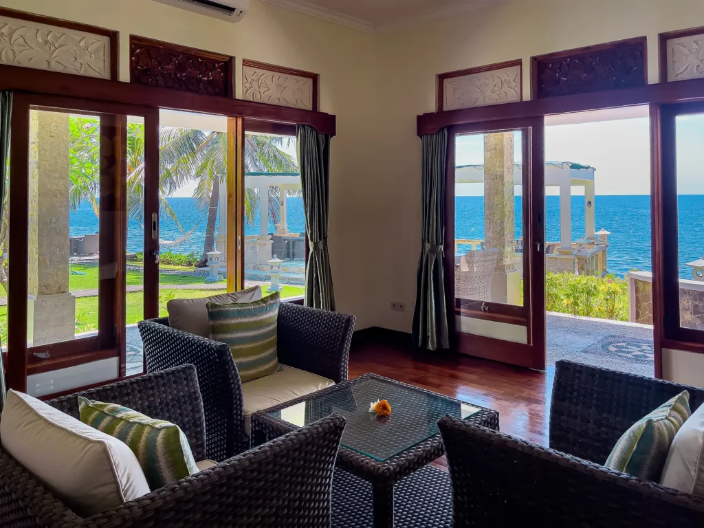 Villa living room with wicker sofas and open doors onto the ocean