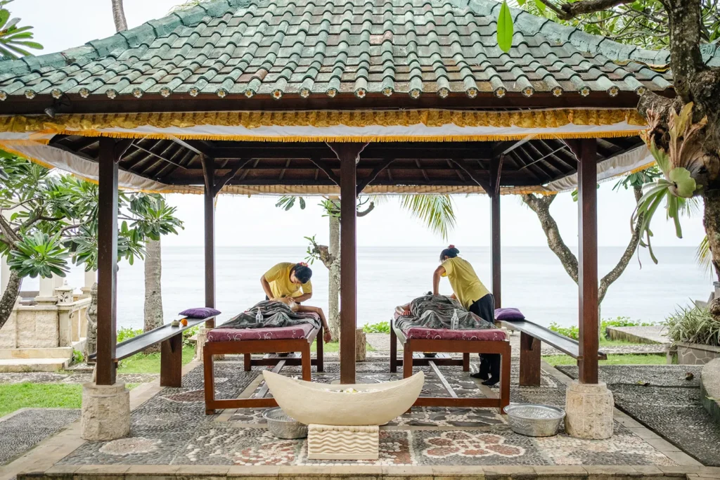 Two guests receiving massages in an open seaside bale