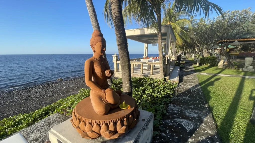 Stone Buddha statue on the black-sand beach in front of the resort