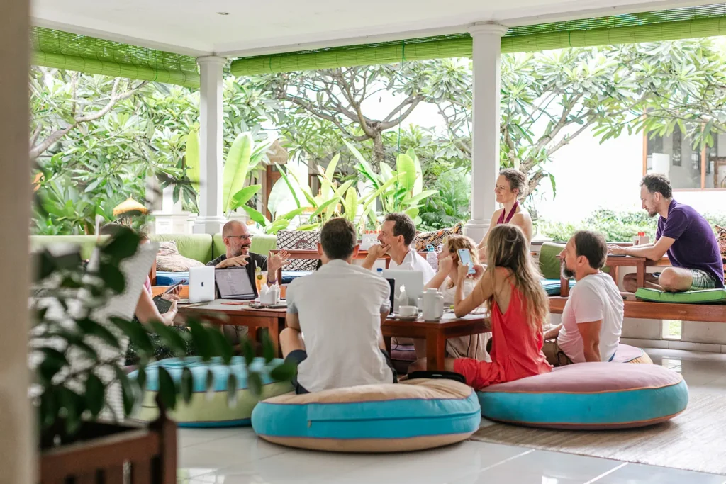 Group seated on floor cushions in an open pavilion during a workshop