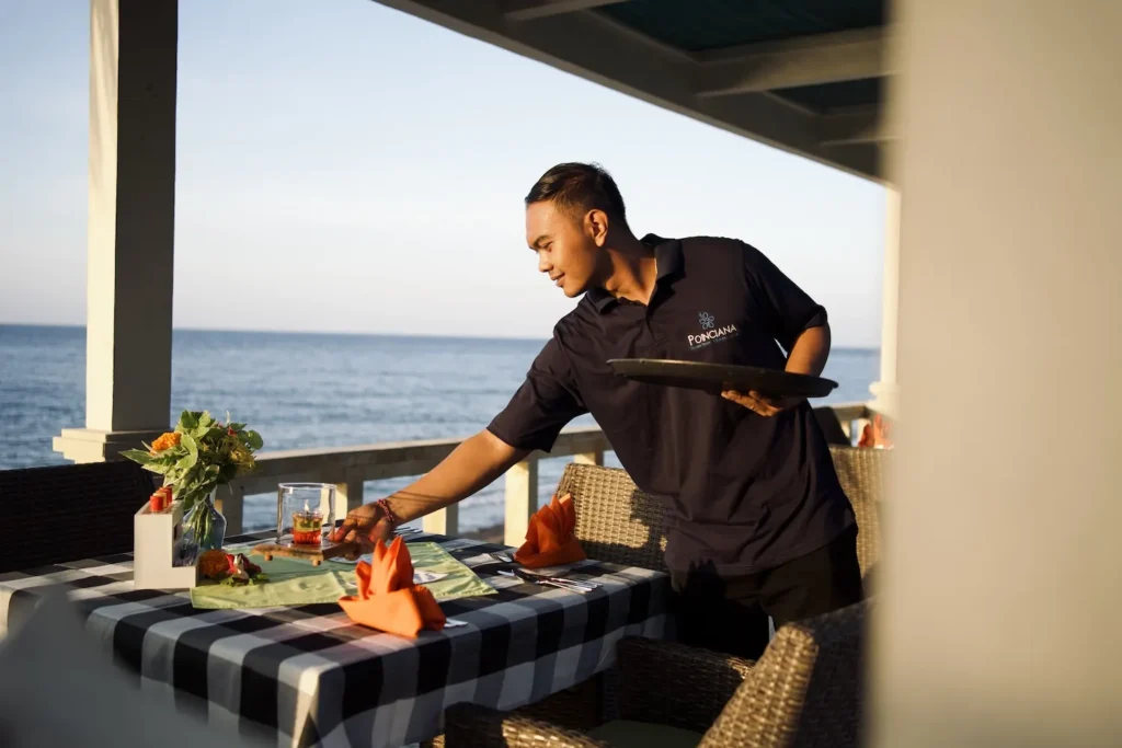 Waiter laying a table for dinner on the seafront terrace