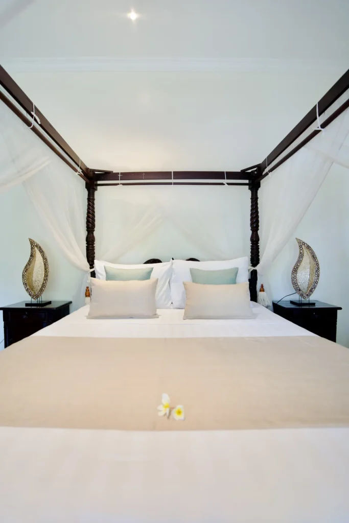 Four-poster canopy bed with white linen in a villa bedroom