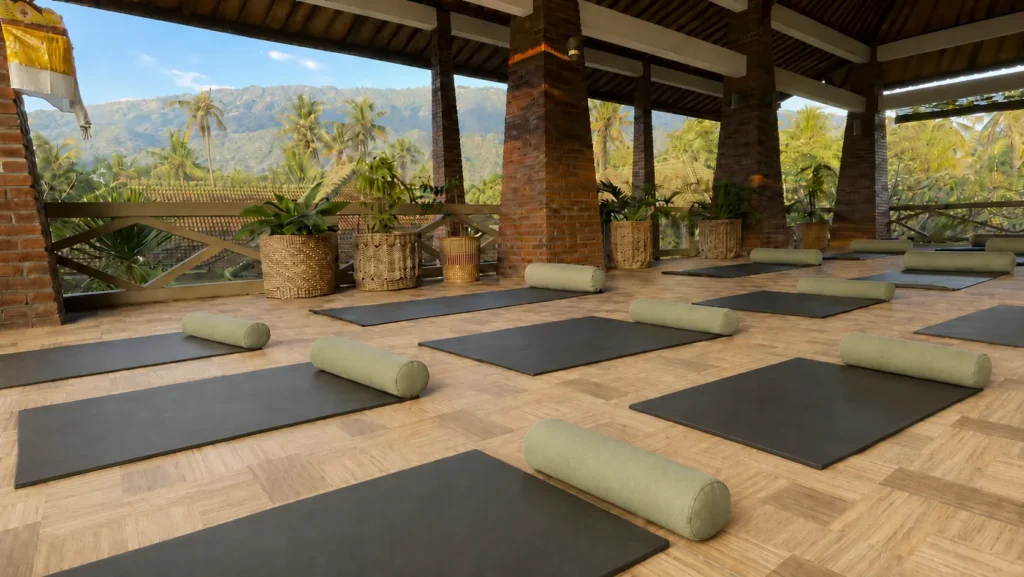 Open-sided yoga shala with mats and bolsters looking toward the mountains