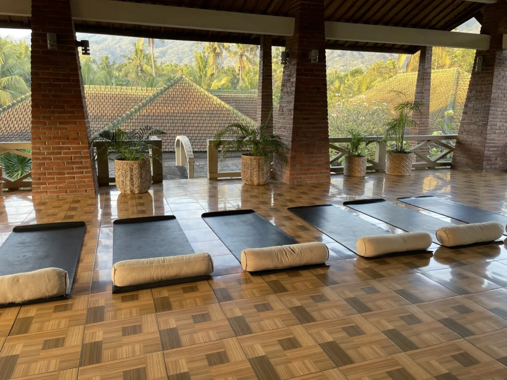 Yoga shala with brick columns and a polished wooden floor, mats laid out
