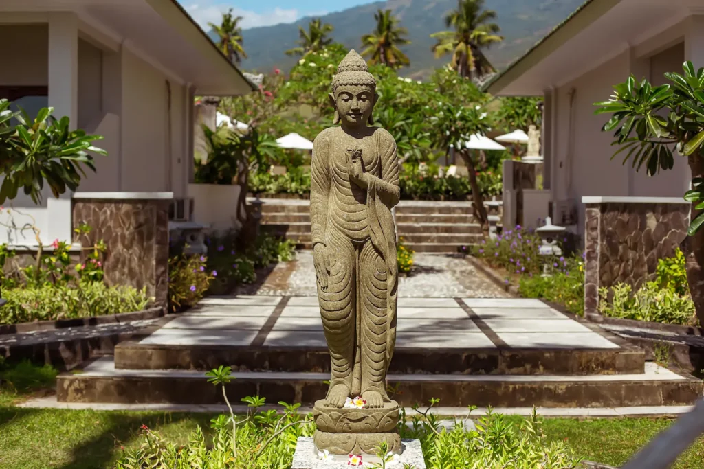 Standing Buddha statue on the garden walkway between the villas